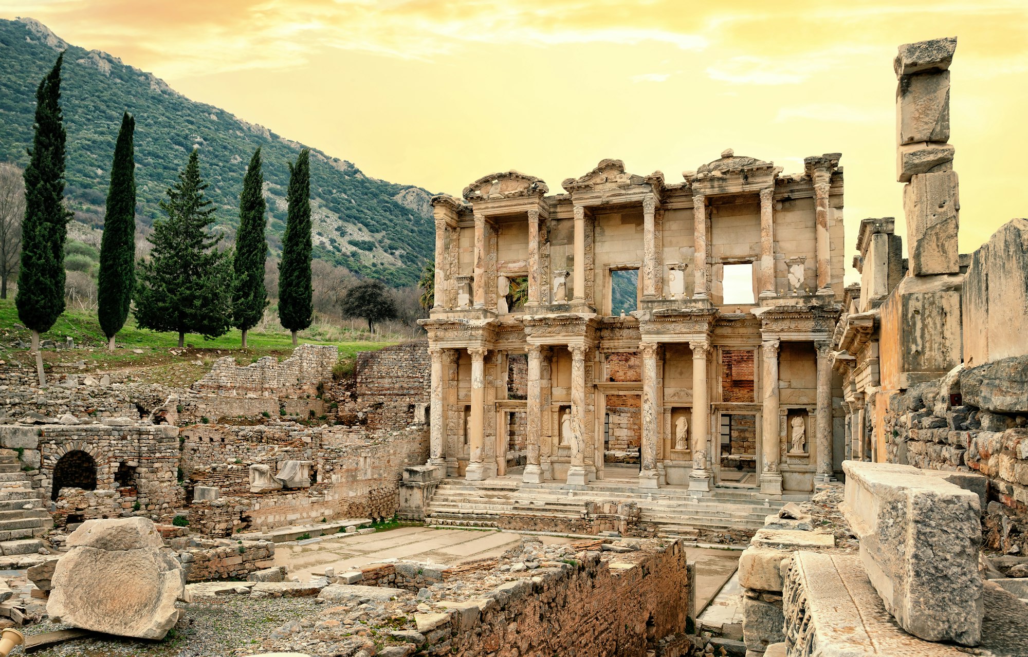 Facade of Library of Celsus in Ephesus under yellow sky